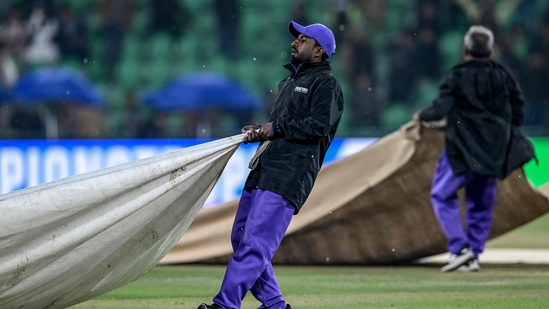 Groundmen cover the pitch as rain stops play during the ICC Champions Trophy one-day international (ODI) cricket match between Australia and Afghanistan at the Gaddafi Stadium in Lahore on February 28, 2025. 